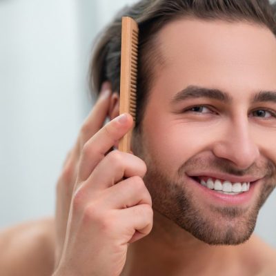 Smiling man doing hairstyling and looking contented